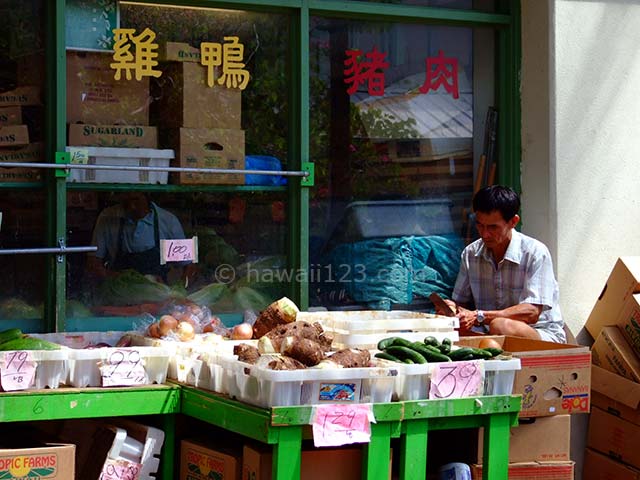 チャイナタウンの肉屋の軒先で野菜を売っている光景
